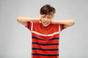 autistic child covering his ears