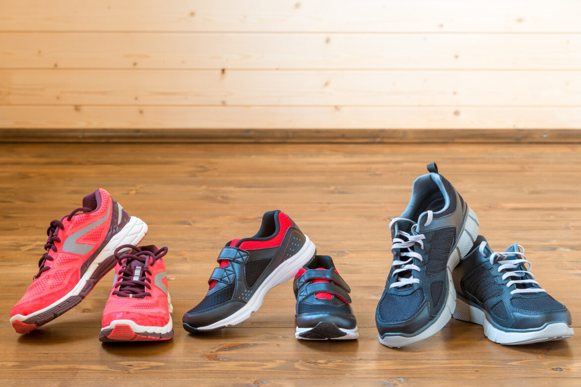 Three pairs of sports sneakers on a wooden floor close-up